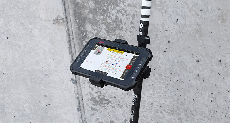 Leica iCON trades software for layout on black tabled attached to Leica iCON vPole in front of concrete wall.